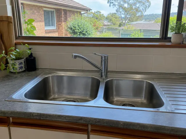 Chrome kitchen tap above a double stainless steel sink with tiled splashback and stone benchtop in Jannali